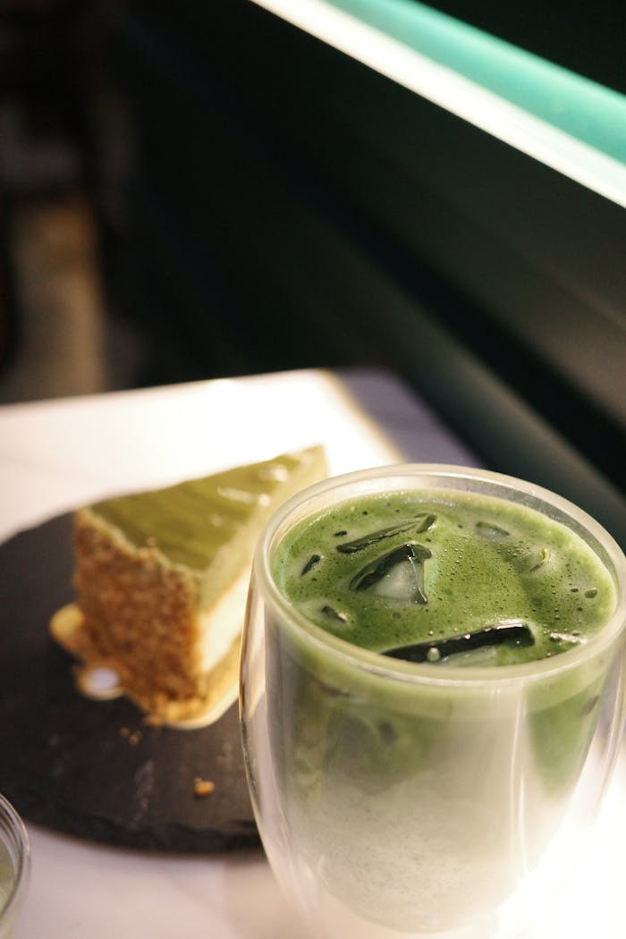 Refreshing iced matcha latte with a delicious slice of matcha cheesecake, perfect for tea lovers.