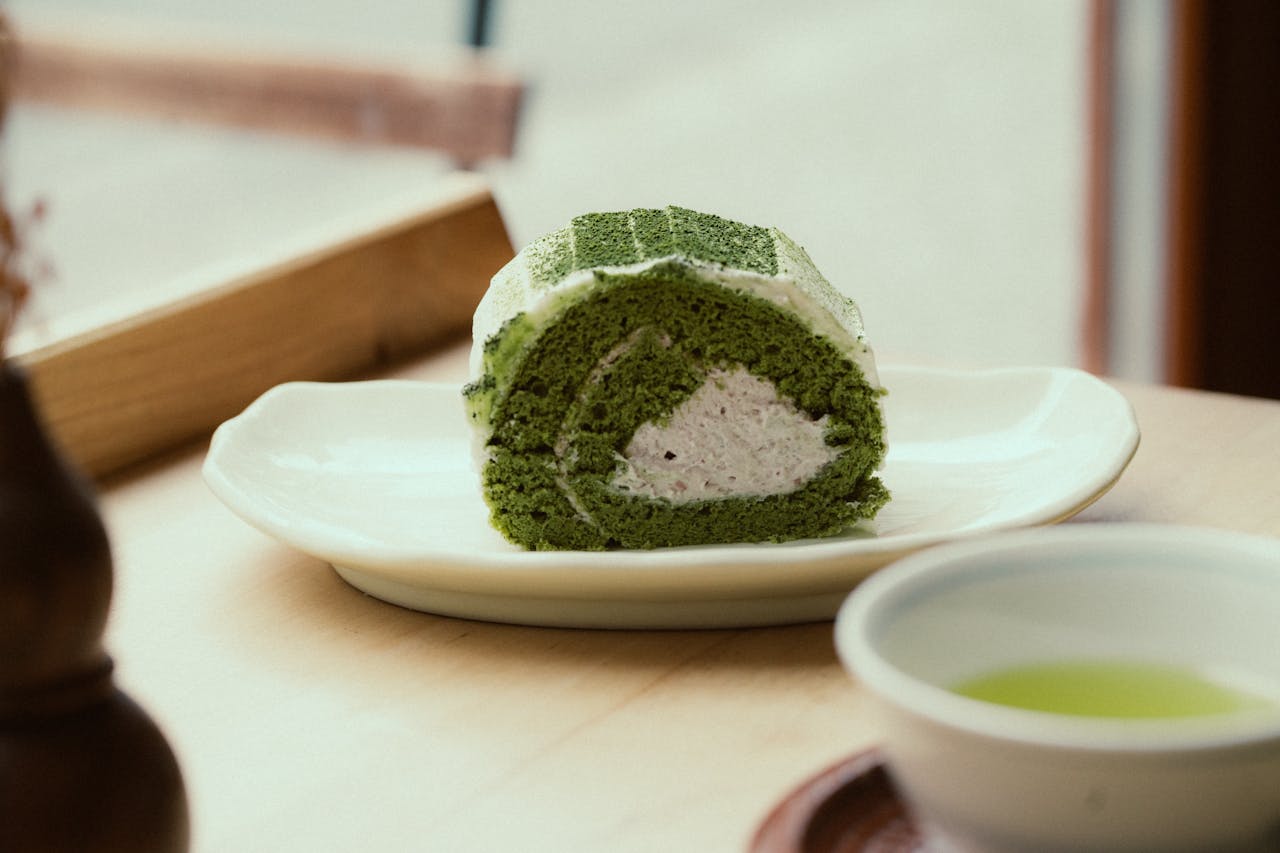 Tasty matcha Swiss roll cake served with tea on a plate, perfect for dessert cravings.
